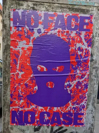Violett Baclava with violett text "NO FACE - NO CASE" on orange and violett background as a poster pasted on a grey electrical box